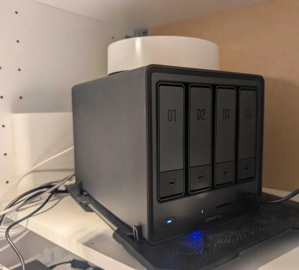 NAS UGREEN DXP4800 Plus installé dans un placard, avec la box Internet posée dessus